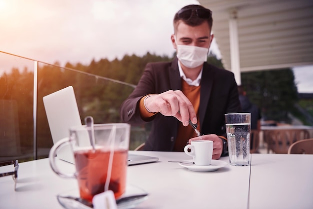 man zit gescheiden in restaurant koffie te drinken met een medisch beschermend gezichtsmasker om infectie te beschermen tegen coronavirus covid-19, concept van sociale afstand