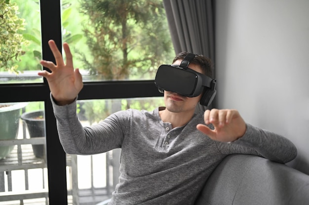 Man zit in de woonkamer en draagt een virtual reality-bril die een videogame speelt