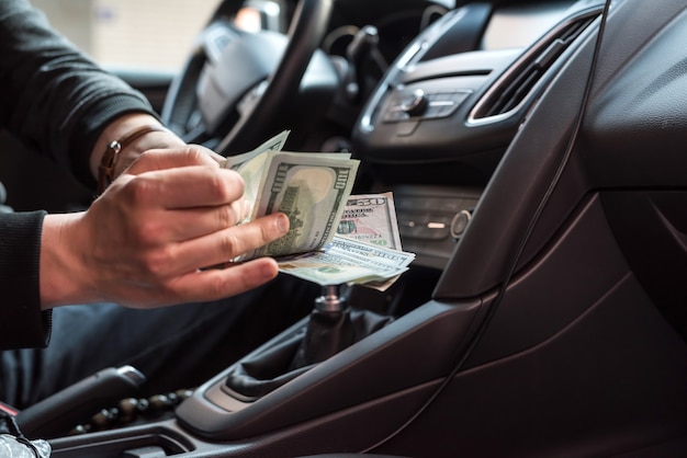 Man zit in een auto dollar biljetten tellen als steekpenningen