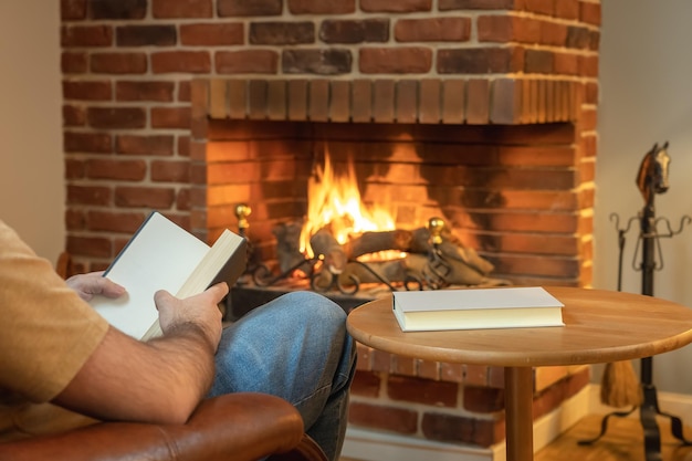 Man zit in een fauteuil en leest op een ontspannen manier een boek voor het haardvuur in de winter