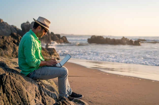 Man zit met een laptop alleen op het strandx9