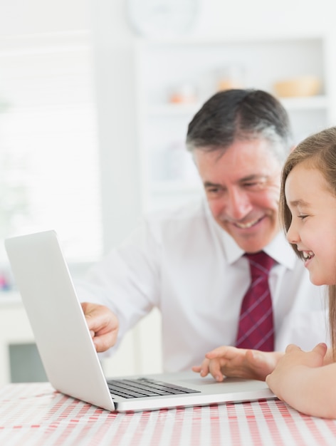 Man zit met zijn dochter in de keuken op laptop