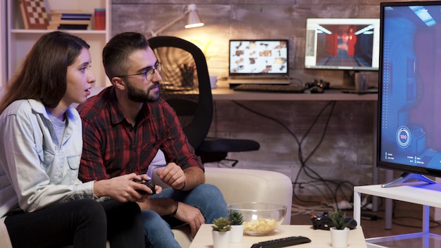 Foto man zit op de bank en leert zijn vriendin videogames op televisie te spelen.