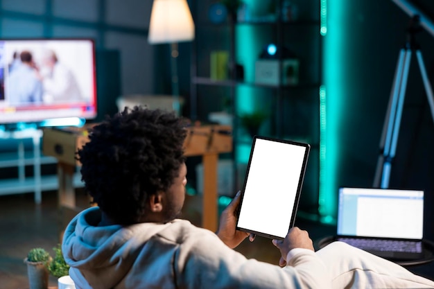 Man zit op de bank en leest een e-boek van een tablet in een appartement met behulp van een mockup tablet