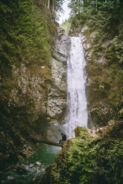 Man zit op de berg tegen een waterval in het bos.