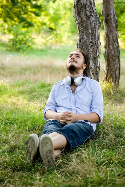 Man zit op groen gras met koptelefoon.