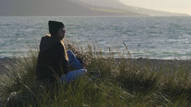 Foto man zit op het gras bij de zee