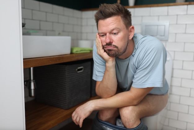 Man zit op toilet met constipatie en wacht tot het laxeermiddel in werking treedt.