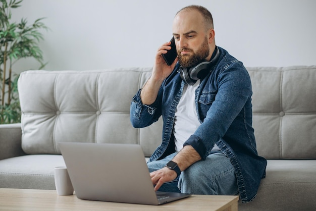 Man zittend op de bank en thuiswerkend op zijn laptop