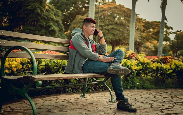 Man zittend op een bankje bellen op de telefoon jonge man zittend op een bankje met mobiele telefoon