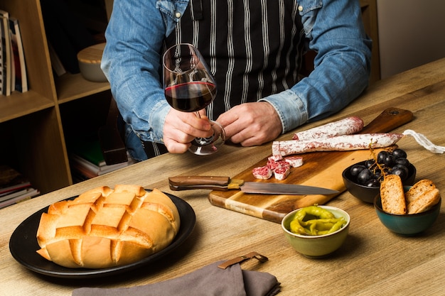 Man zittend op een tafel met hapjes en een glas wijn