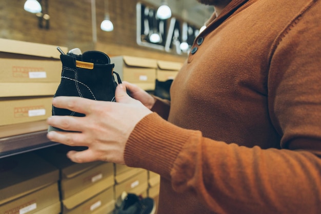 Man zoekt schoenen in de winkel. houd nieuwe schoenen in handen