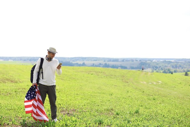 Foto man zwaaien amerikaanse vlag staande in gras boerderij landbouwgebied, vakantie, patriottisme, trots, vrijheid, politieke partijen, immigrant
