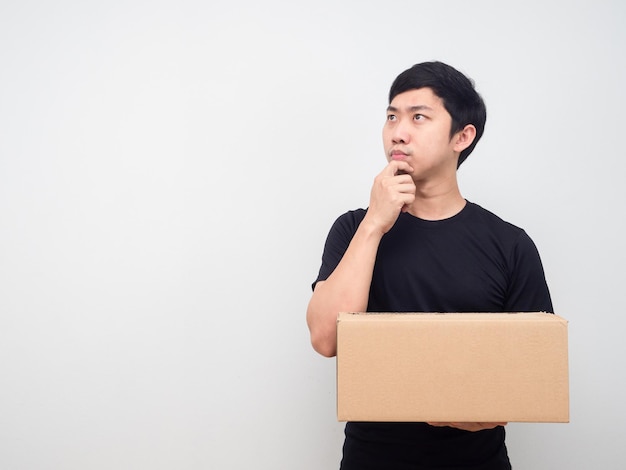 Man zwart shirt met pakketdoos die naar kopieerruimte kijkt en iets denkt