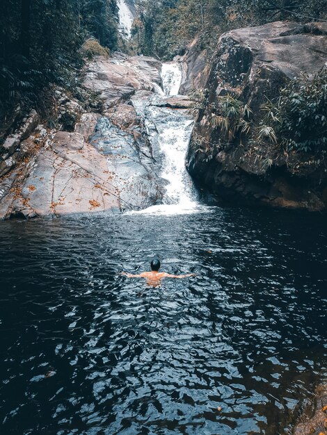 Foto man zwemt bij de waterval.