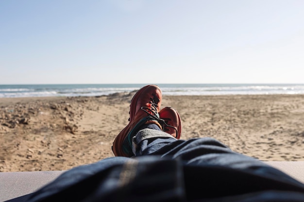 Man39s benen in spijkerbroek en wandelschoenen liggend in een busje op het strand Eenzaamheid man toerist backpacker ontspannen en genieten van prachtige outdoor lifestyle en natuur vakantie