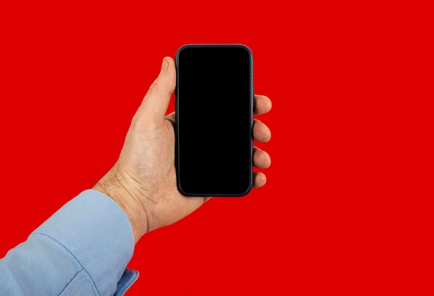 Man39s hand with shirt holding smartphone studio shot red background