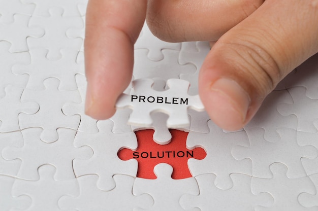 Management concept with hand holding piece of jigsaw puzzle with PROBLEM and SOLUTION wording