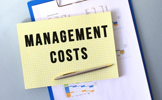 MANAGEMENT KOSTEN tekst geschreven op Kladblok met potlood. Kladblok op een map met diagrammen. Financieel begrip.