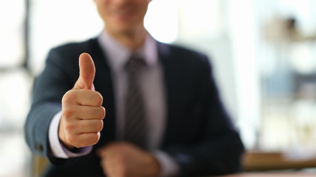 Manager businessman showing gesture thumb up at work in office closeup