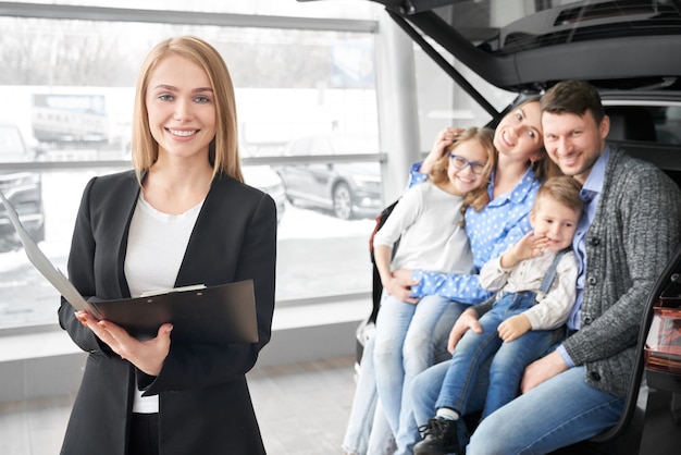 Manager of car dealership and happy family posing, smiling.