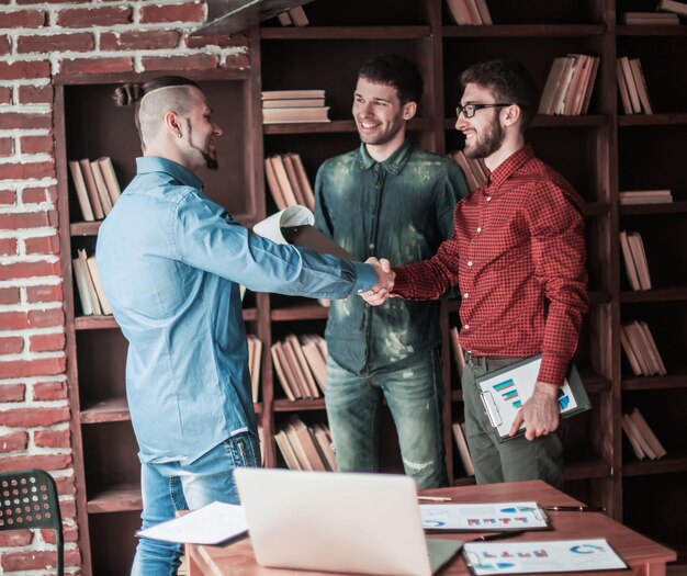 Manager of the company welcomes the customer with a handshake in