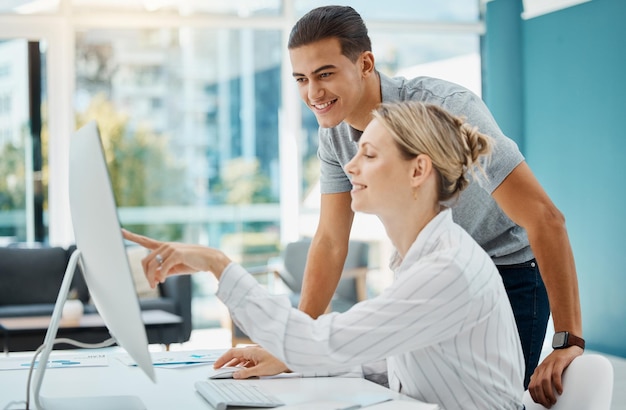 Manager consulting an employee about an online project on a computer in her corporate office Business people working on idea solution and strategy while doing research on internet with technology