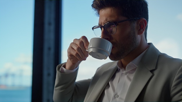 Manager drinken koffie in zeezicht kantoor close-up Zakenman met pauze