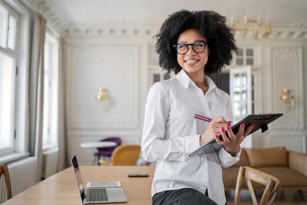 Manager een vrouw met een bril gebruikt een tablet maakt aantekeningen op het werk kantoor werkplaats coworking ruimte