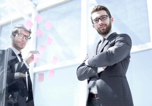 Менеджер и сотрудник, стоящие возле прозрачной доски в концепции офисного бизнеса
