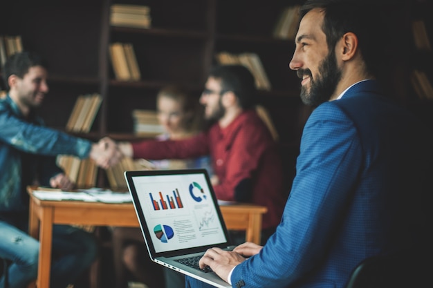 Manager Finance werkt met de marketingafbeeldingen op de laptop met de zakelijke teamwerkplek op kantoor