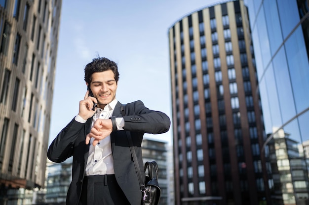 Il manager con gli occhiali è un uomo che parla al telefono per lavorare in ufficio in completo