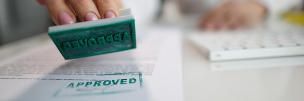 Manager hand putting stamp approved on document in office closeup