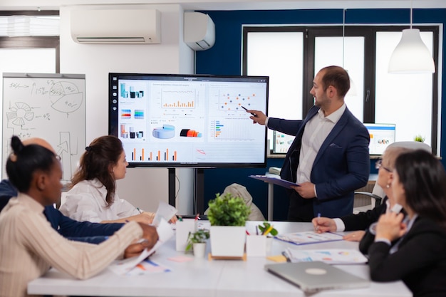 Photo manager holding briefing presentation in conference room monitor project