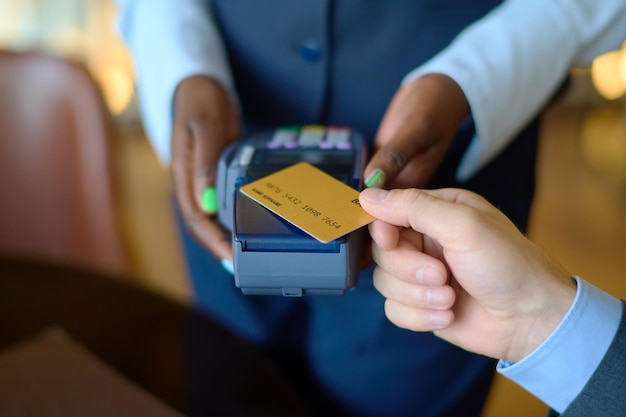 Manager holding payment terminal while man with credit card paying for purchase