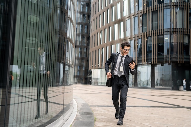 メガネをかけた男性が会社に出勤しているマネージャーはビジネス スーツで電話を使用しています