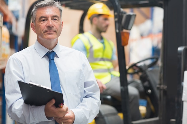 Manager posing in front of his employee in warehouse