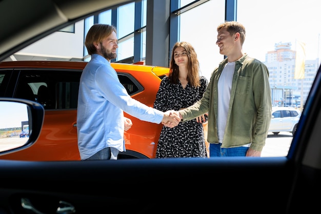 The manager shakes hands with a man at the dealership A married couple bought a new car