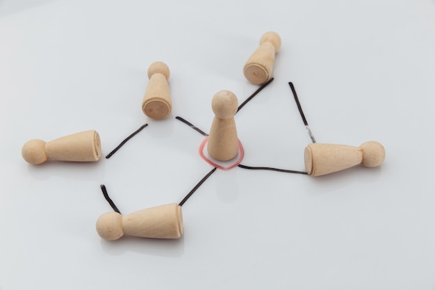 Manager and a team. Wooden figures on a white wall. Concept of teambuilding, leadership and management.