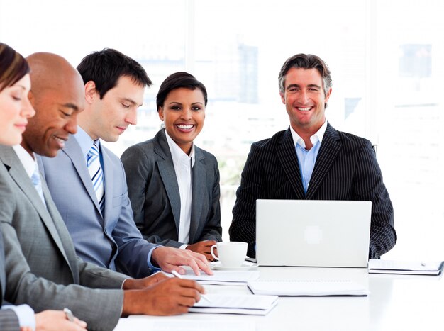 Manager usimg a laptop in a meeting with his team