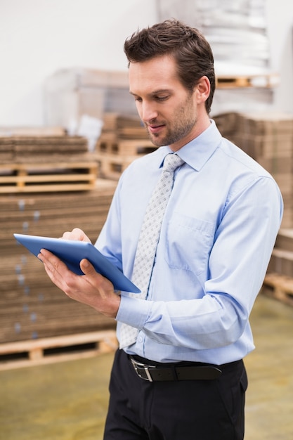 Manager using digital tablet in warehouse