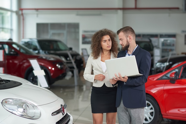 Manager van autodealer die auto toont aan vrouw.