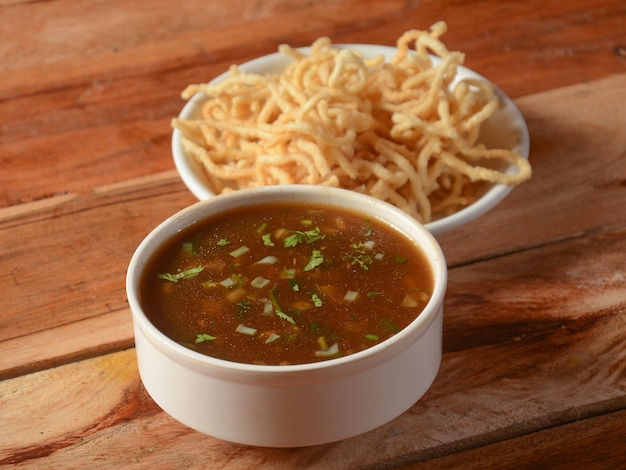 Manchow soup indo chinese dish served over a rustic wooden background selective focus