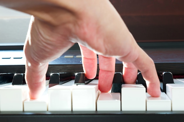 Mand hand playing piano. Low angle point view. Sunlight through and bokeh. Art background.