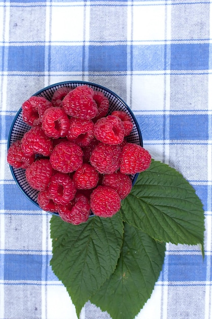 Foto mand met rijpe frambozen op houten tafel in een tuin