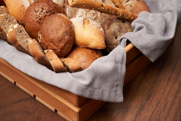 Mand met vers brood op houten tafel achtergrond. Verscheidenheid aan bakkerijbroodproducten in mand