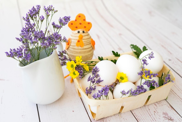 Mand met witte eieren en verse bloemen op houten achtergrond