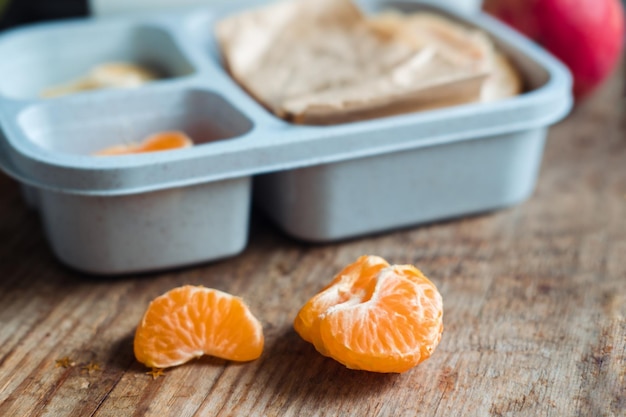 Mandarijn plakjes close-up op houten achtergrond in de buurt van lunchbox