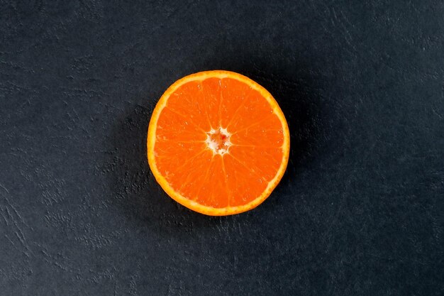 Половина ломтика апельсина мандарина на черном фоне
