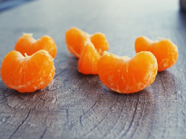 Mandarin slices lie on a wooden background